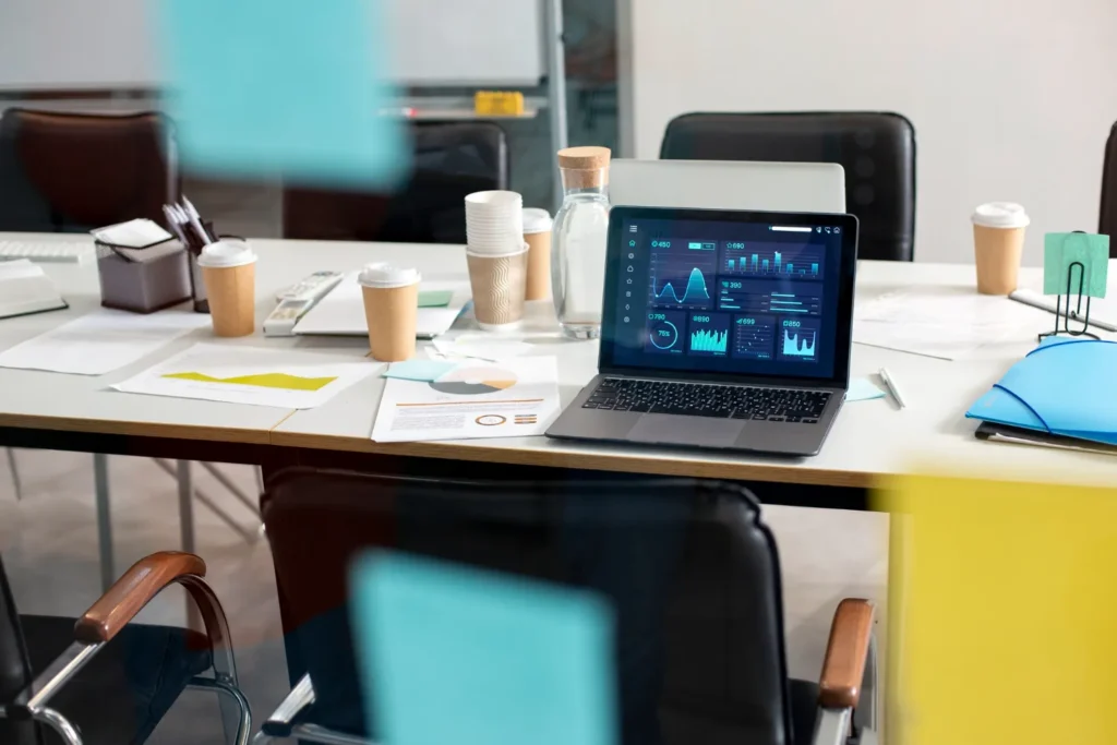 Modern digital marketing office with laptops, analytics dashboard, and coffee cups on meeting table